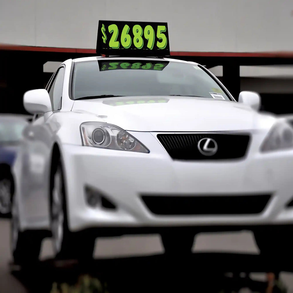 Car Top Sign with pricing numbers on a dealer lot.