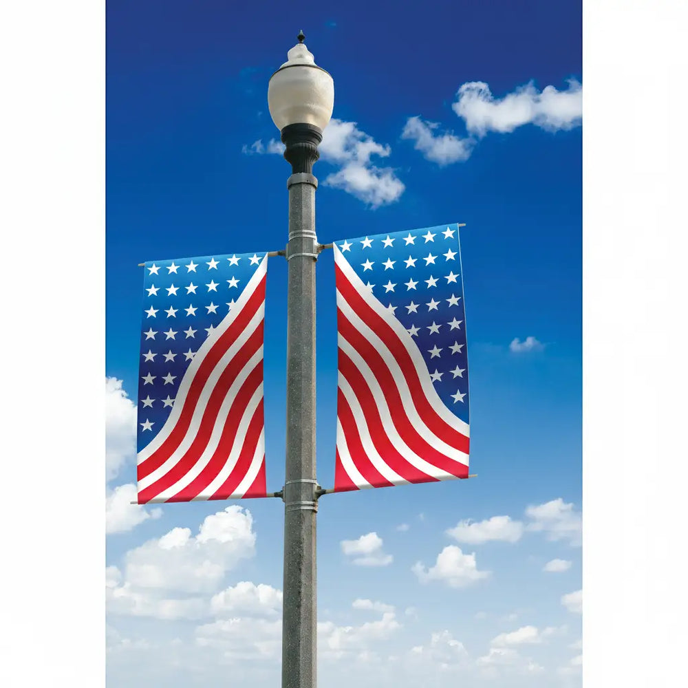 Two American flags on a pole against a blue sky with white clouds